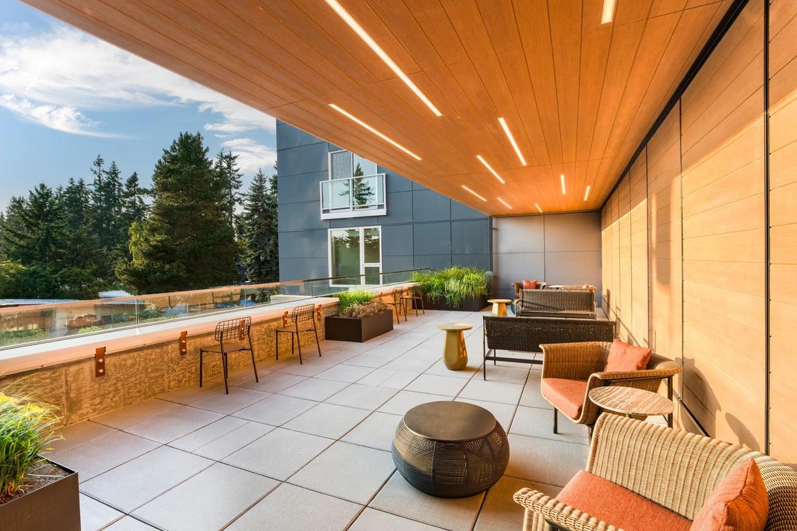 Relax beneath warm wood accents on Modera Shoreline's terrace, offering inviting seating and tranquil treetop views.