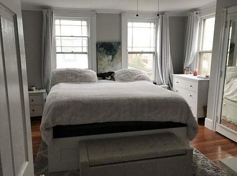 Large bedroom with lots of natural light and hardwood floors.
