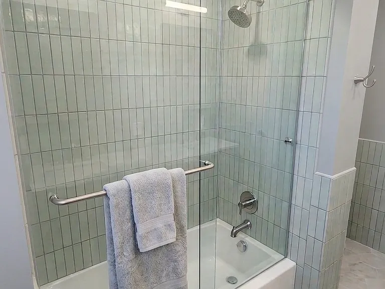 Upstairs bath with glass barn-door top hung doors.