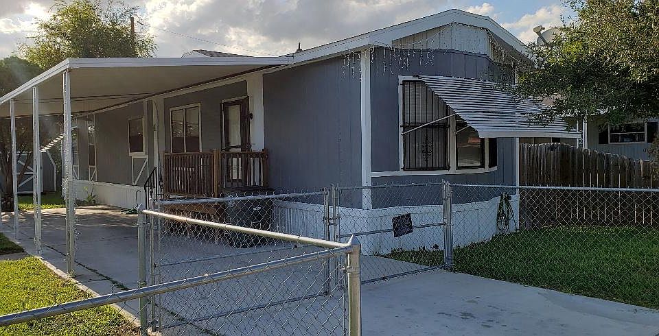 Mobile home entrance with front chain link and wooden privacy in back. Front gate has space to park a small vehicle without opening gate.