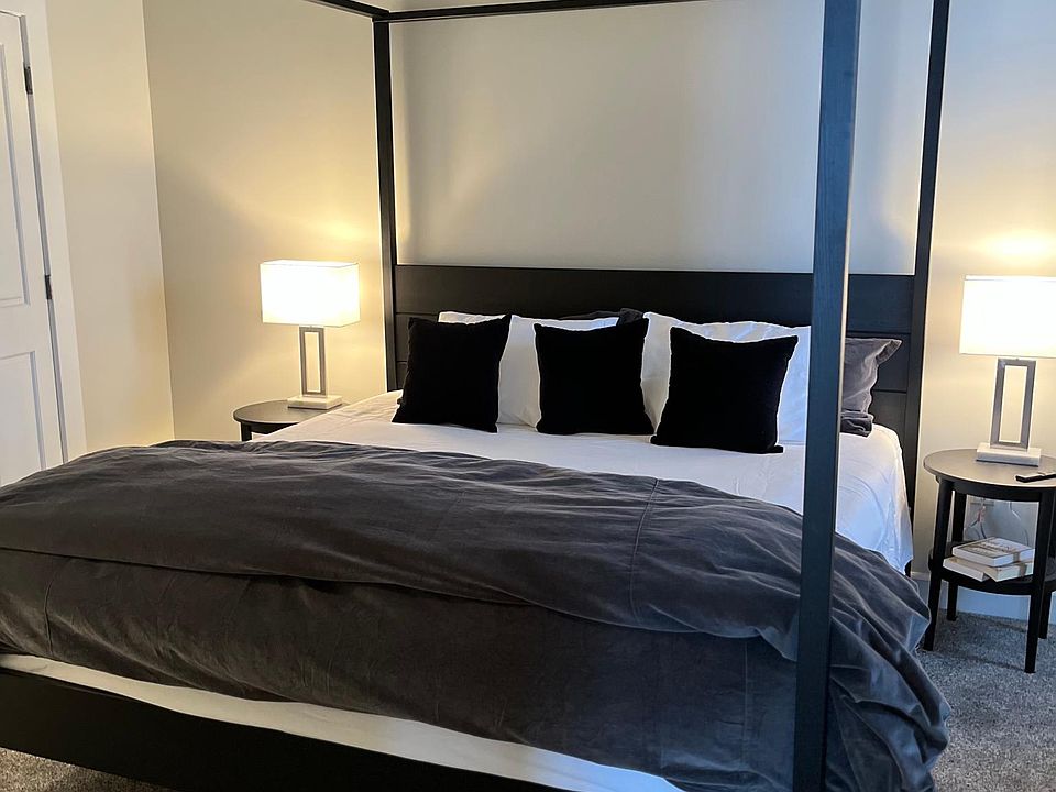 Master bedroom with 4-post king bed and modern linens.