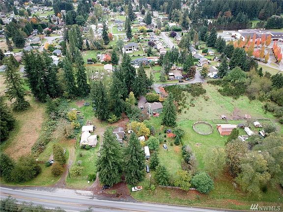 View of property from the front. House is partially hidden from view from 2 large trees in front.