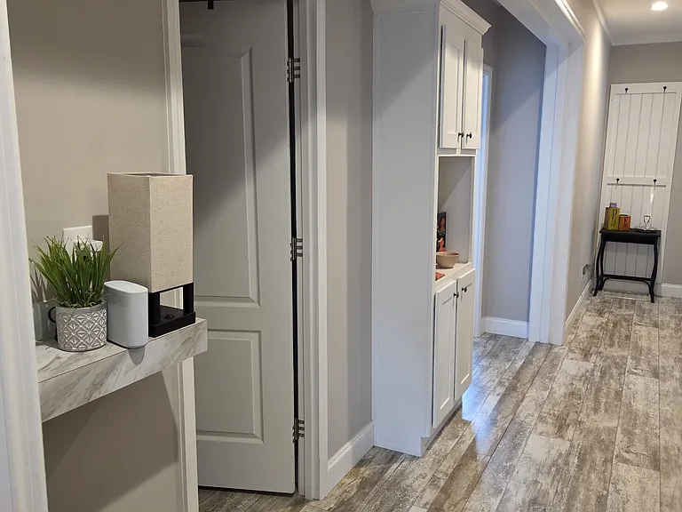 Large long hallway with linen cabinet, display shelf and mudroom wall rack