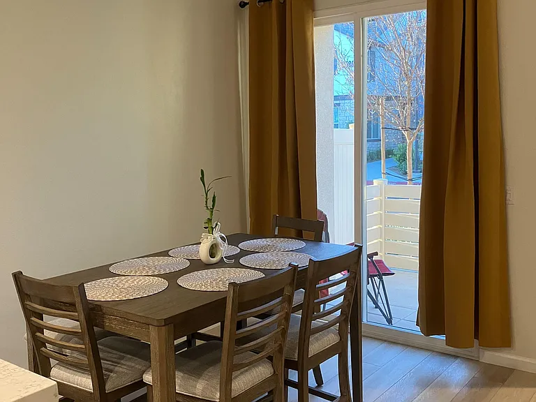 Dining area with a full-size table, durable flooring, and sliding glass doors leading to a private patio.