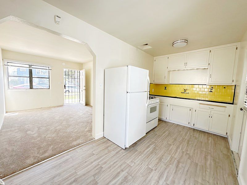 New LVP Flooring in kitchen, appliances include fridge/freezer, gas range stove and features 50's retro tiling!