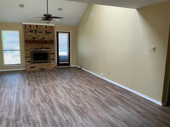 living room featuring ceiling fan, vaulted ceiling, wood-type flooring, and a brick fireplace