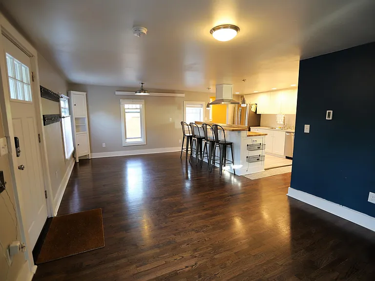 Standing in living room, viewing dining room on left beyond the door, and kitchen island to the right.
