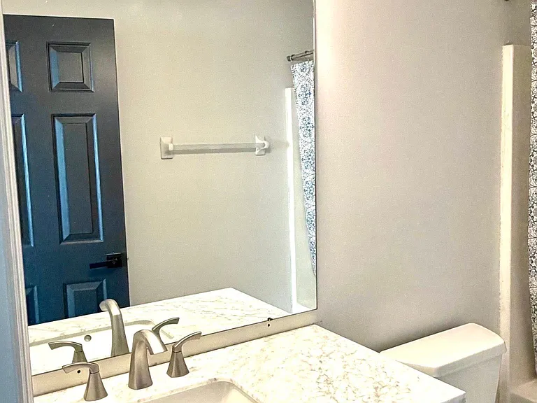 Shared hall bath with tub/shower combo and new marble-topped vanity and lighting.