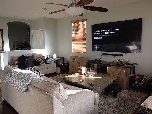 Living room with front door behind small wall and arched entry to office