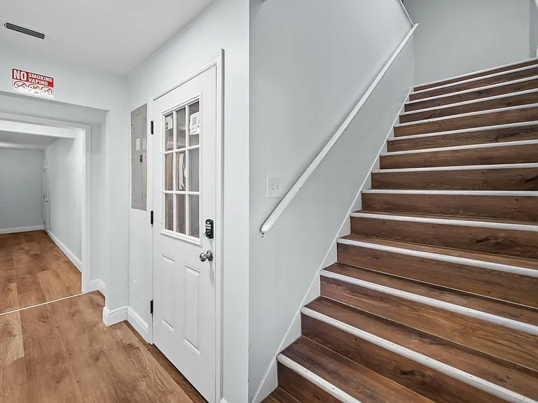 Clean entry hallway with durable wood-look flooring, interior stair access, and a secure door with keypad lock.