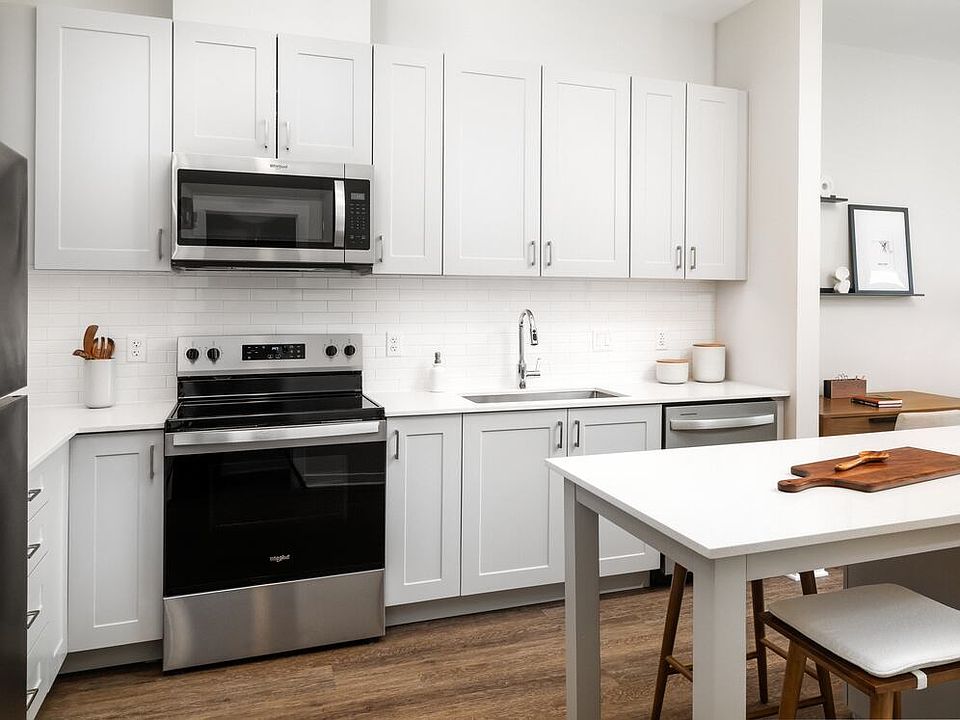 New West Phase - Finish Package III Kitchen with stainless steel appliances, white quartz countertops, grey cabinetry, pendant lighting, and hard surface flooring