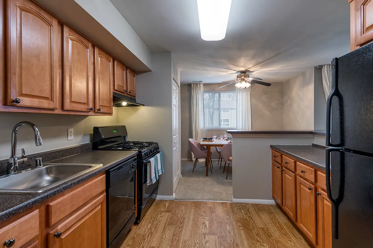 Designer Kitchens With, Wood Flooring, Sleek Black Appliances & Solid Wood Cabinets - The Brook At Columbia