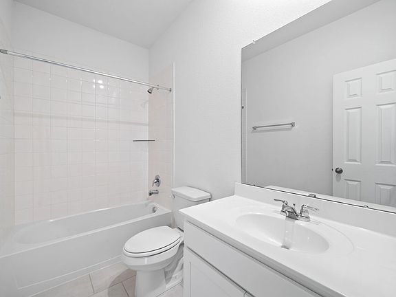 The second bath features tile flooring, white cabinetry and light countertops and a shower tub combo