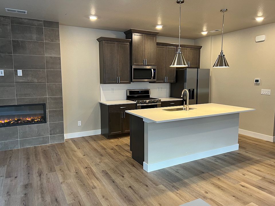 Kitchen with counters, cabinets, sink and food serving island. The fireplace is on the left.