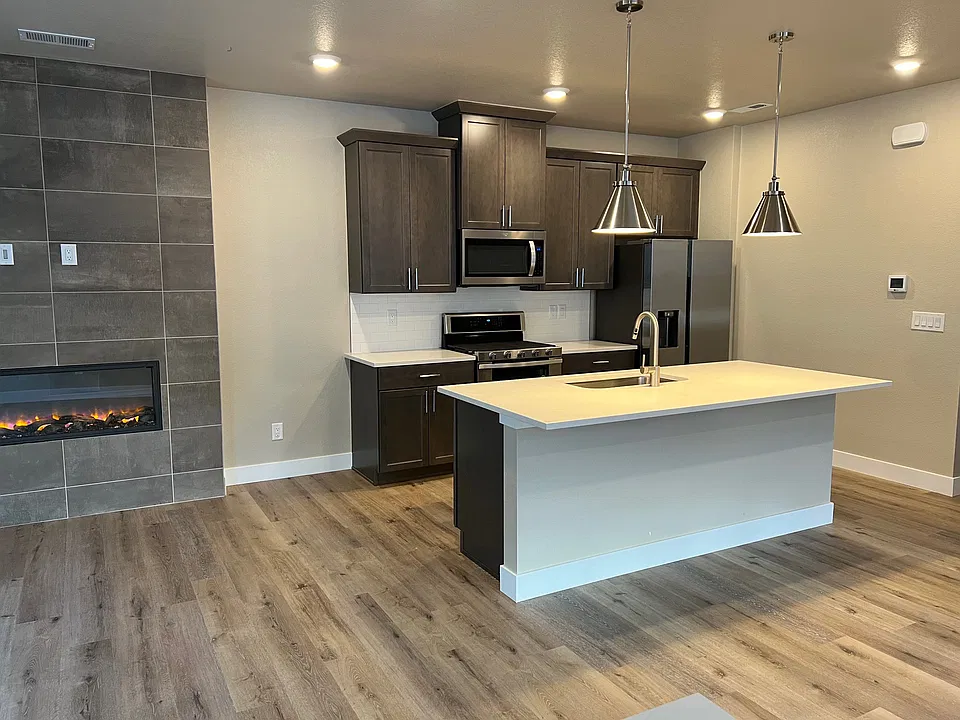 Kitchen with counters, cabinets, sink and food serving island. The fireplace is on the left.