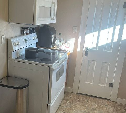 Electric stove, microwave and air fryer. Door leads to large pantry. Lots of storage!