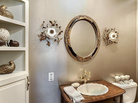 The powder room features metallic paint, an antique vanity and built-in storage. (Sconces excluded)