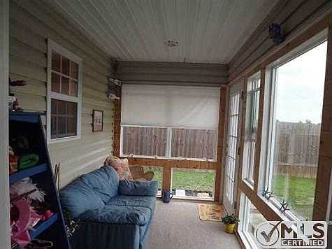 All glassed in sun room overlooks backyard.