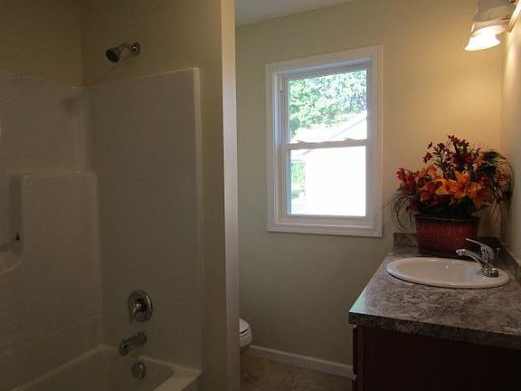 One piece bath shower ensemble, wall separating shower and toilet. Cabinet has same countertop as kitchen, 4 covered light fixture, mirror still to come.