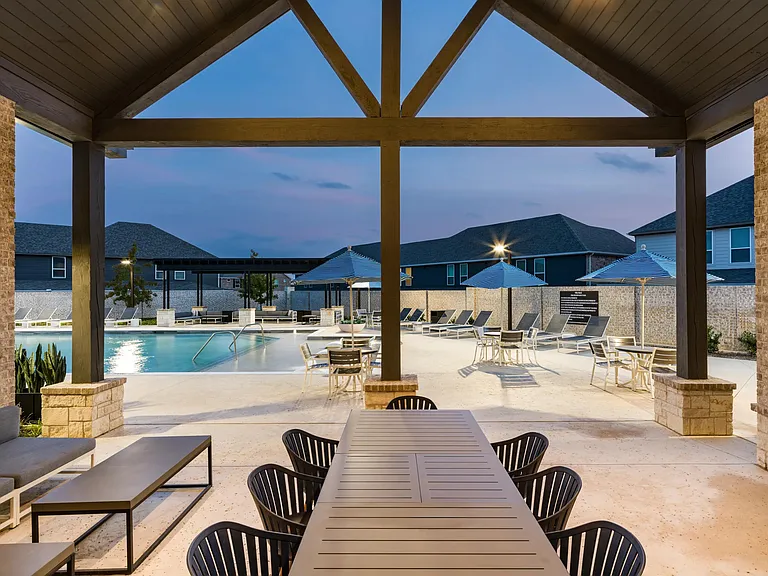 An open-air pool pavilion at Amavi Celina with communal tables, shaded seating, and evening lighting that sets an inviting tone for outdoor gatherings.