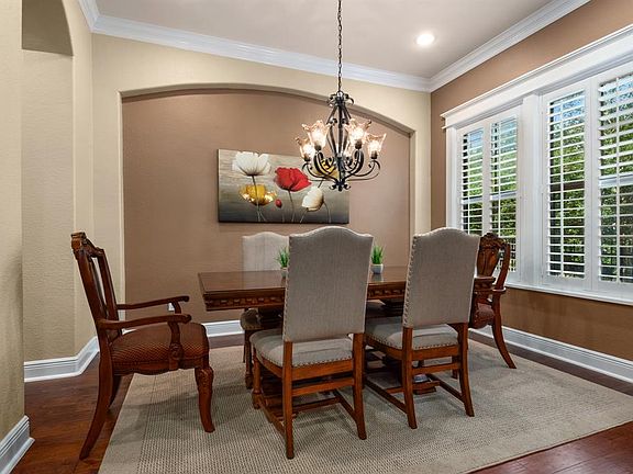 This gorgeous formal dining room has plantation shutters, hardwood floors, beautiful crown molding and arched entryways.