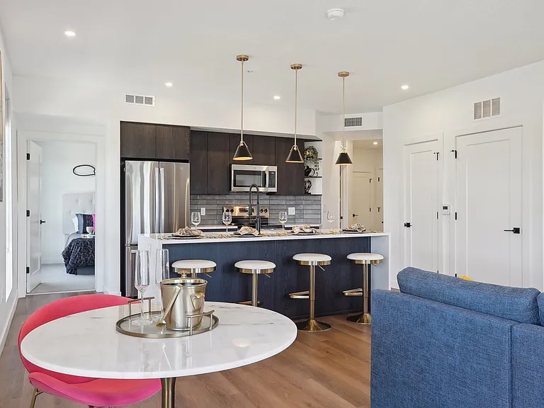 Liberty Duet Apartments, Salt Lake City, Utah; A modern kitchen with a bar stool and a blue sofa.