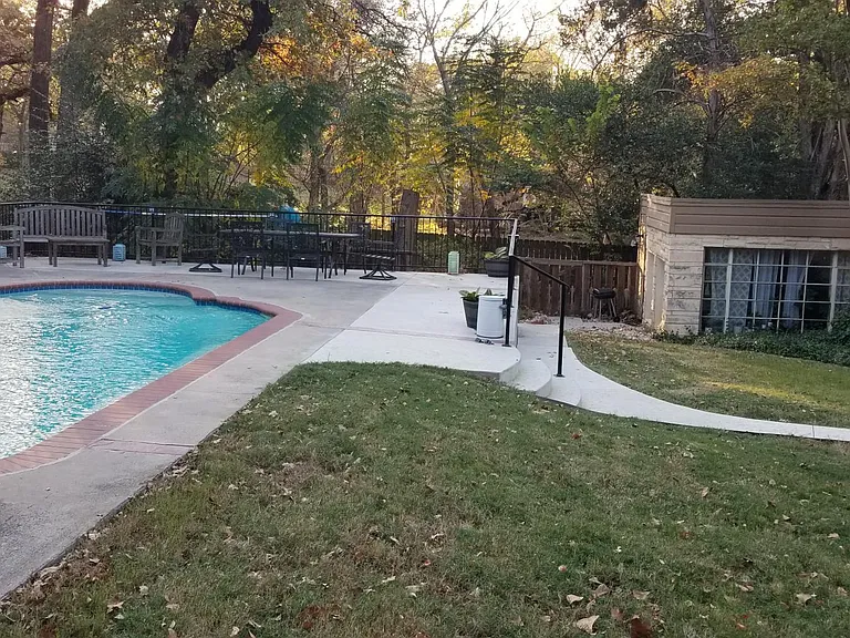 An older picture of the pool deck and back side of bungalow/apartment with dog run. Windows have been replace in the back room (Rm #2). Pool has also been recently redone with darker pebbles.