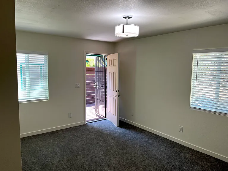 Bedroom #1 with large space, light filled, plush carpet and outdoor entry to private deck.