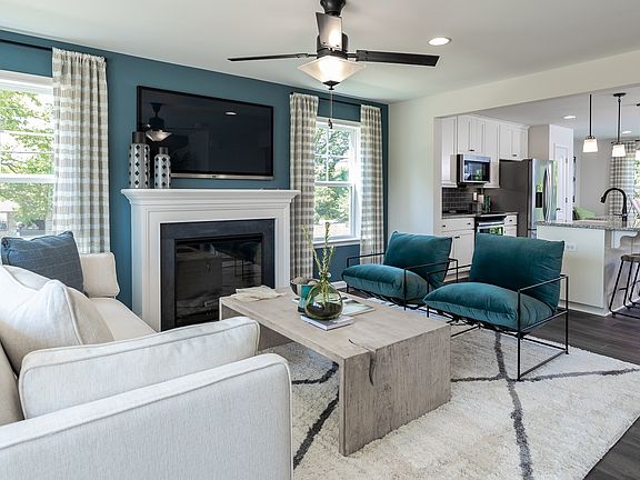 Living room with fireplace and adjacent kitchen in a DRB Homes York II model at the Townes at Tate M