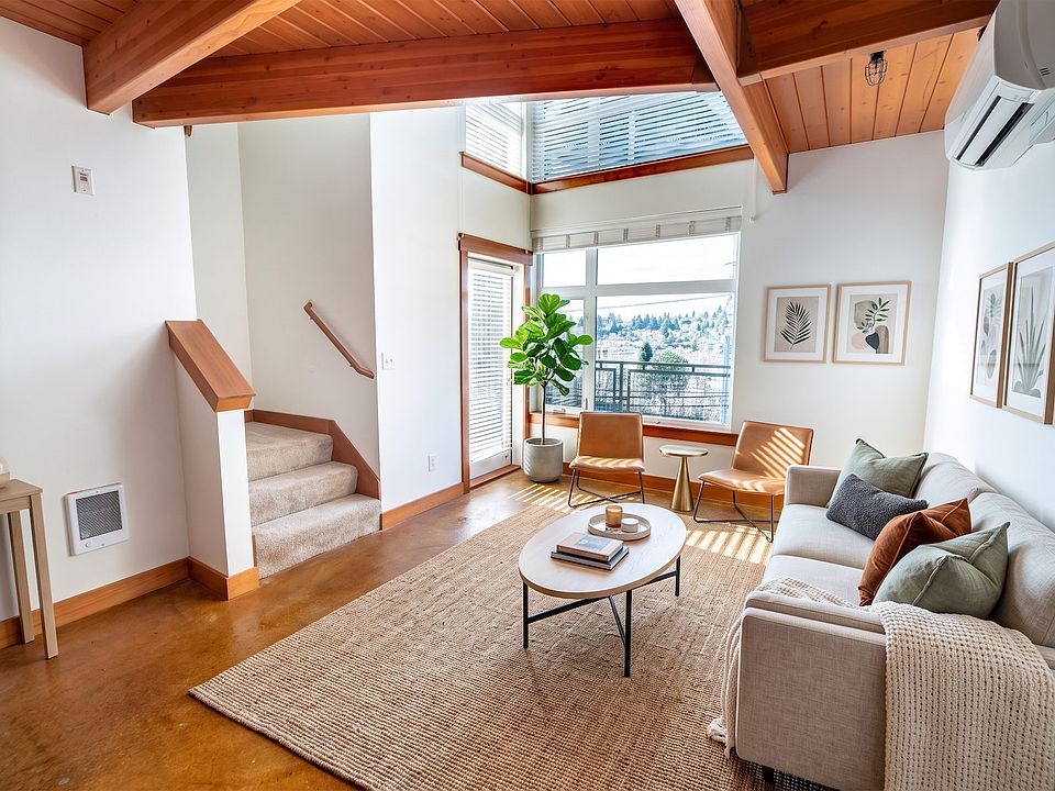 Bright living space with vaulted wood ceilings, large windows, and stairs leading up at Union Bay Lofts in Seattle.