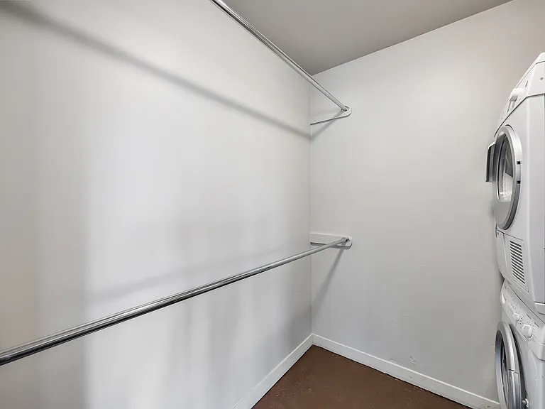 Dedicated utility room with a stacked washer and dryer plus added storage.