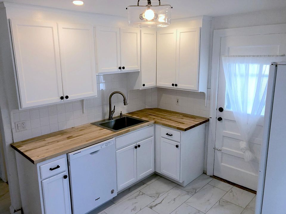 Newly renovated kitchen with dishwasher, fridge, stove, and porcelain floor tile.