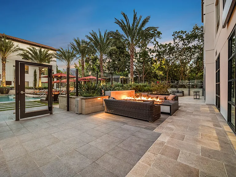 Fire pit lounge with woven seating and palm-lined views