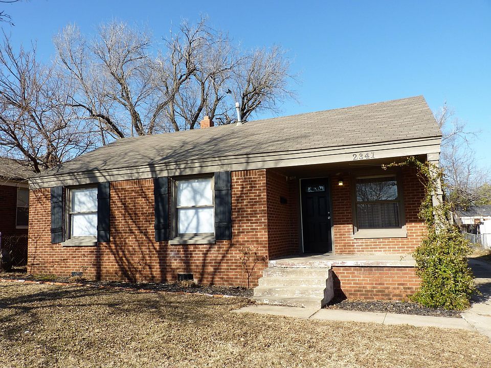 Brick house with a front porch, brick-lined flower beds