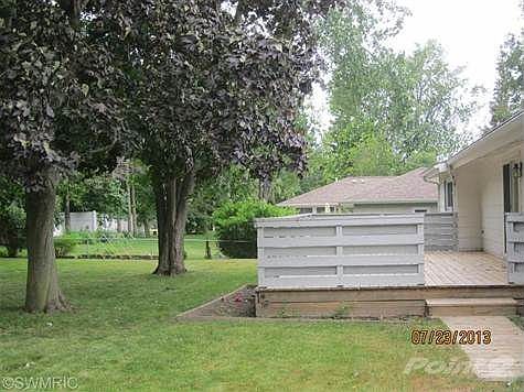 Large yard with big trees for shade and a large deck with walkway to garage.