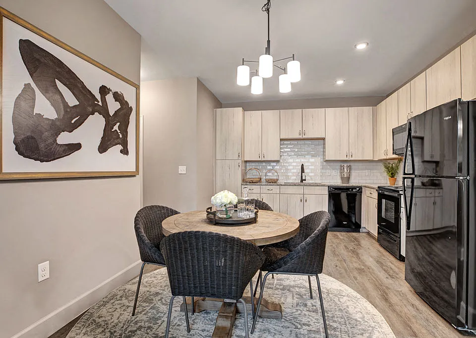 Light ceiling-reaching cabinetry, wood-like plank flooring, sleek black appliances, and white subway tile backsplash