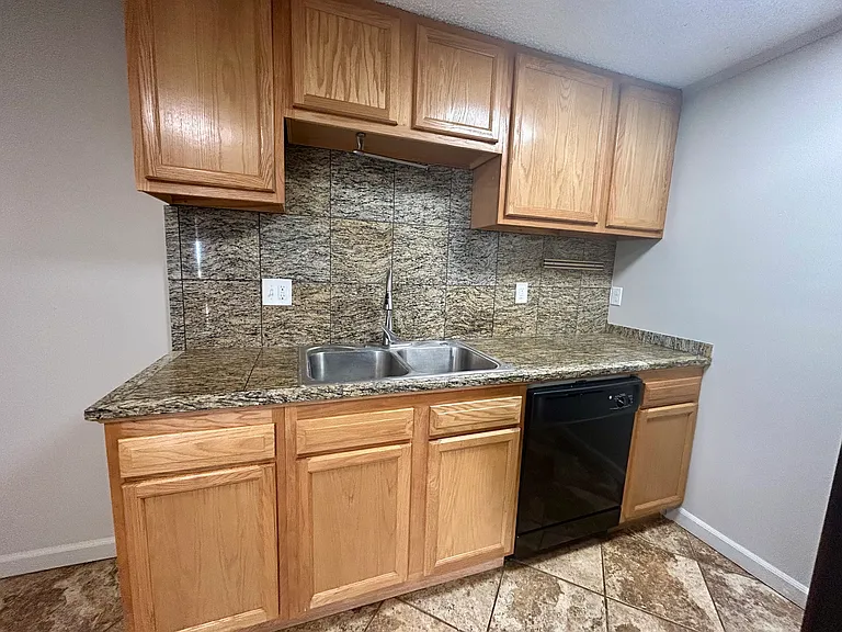 Modern kitchen with sleek granite countertops, wooden cabinets, and black appliances in a stylish apartment setting. Modern kitchen with sleek granite countertops, wooden cabinets, and black appliances in a stylish apartment setting.
