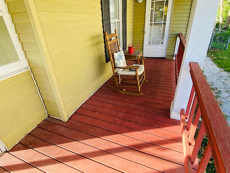 The first bedroom exterior door opens to the bright six light-lit front-side covered porch. It is one of the many outdoor living spaces tenants enjoy day or night. There is space for a porch swing, hammock, dining table, and chairs, and two safety-covered
