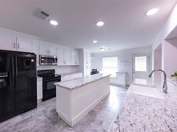 Large kitchen with farm-style sink, granite countertops and custom, oversized island with storage