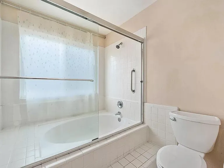 Master Bathroom sunken tub shower. All white.