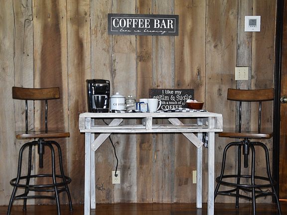 Charming built-in coffee bar set against a stunning reclaimed barn-wood accent wall. A whitewashed farmhouse table pairs with industrial-style stools to create the perfect spot for your morning brew. Thoughtful rustic details and warm hardwood floors!!