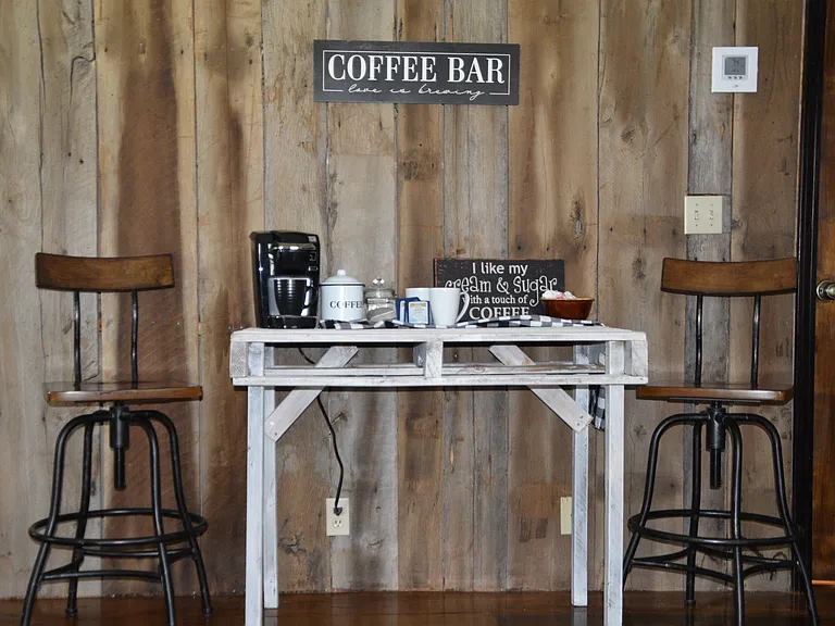 Charming built-in coffee bar set against a stunning reclaimed barn-wood accent wall. A whitewashed farmhouse table pairs with industrial-style stools to create the perfect spot for your morning brew. Thoughtful rustic details and warm hardwood floors!!