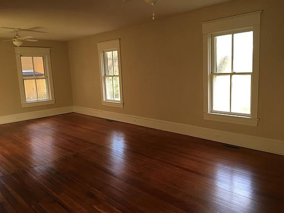 Empty living and dining room--fireplace not in view but to left. Shows second window along front.