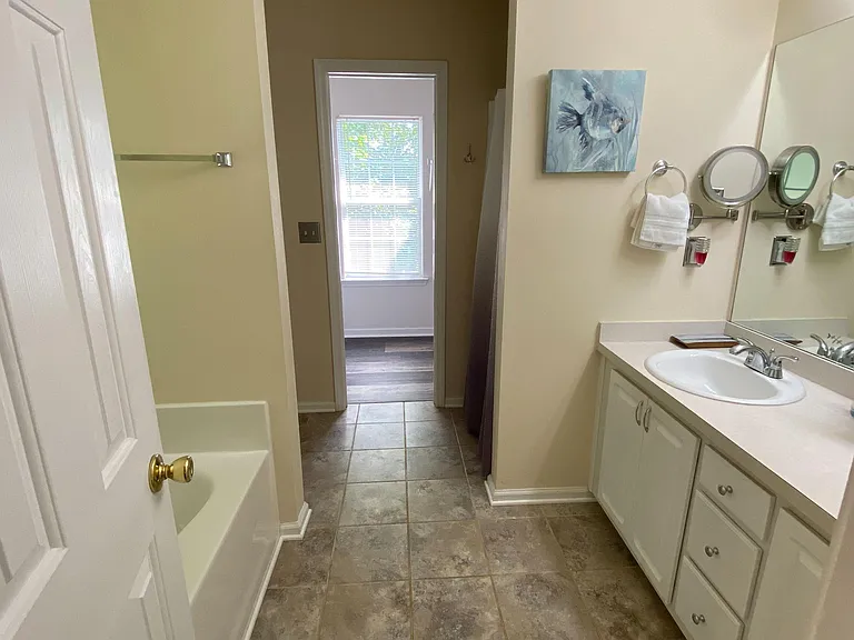 Full bath with vanity storage, large mirror, and tiled flooring, plus a tub/shower combo for easy daily routines.
