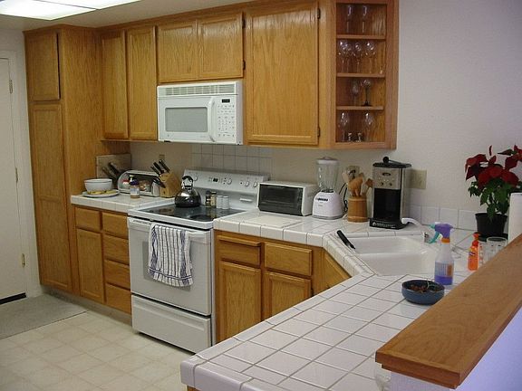 Kitchen features white appliances, white tile counters and walk in closet.