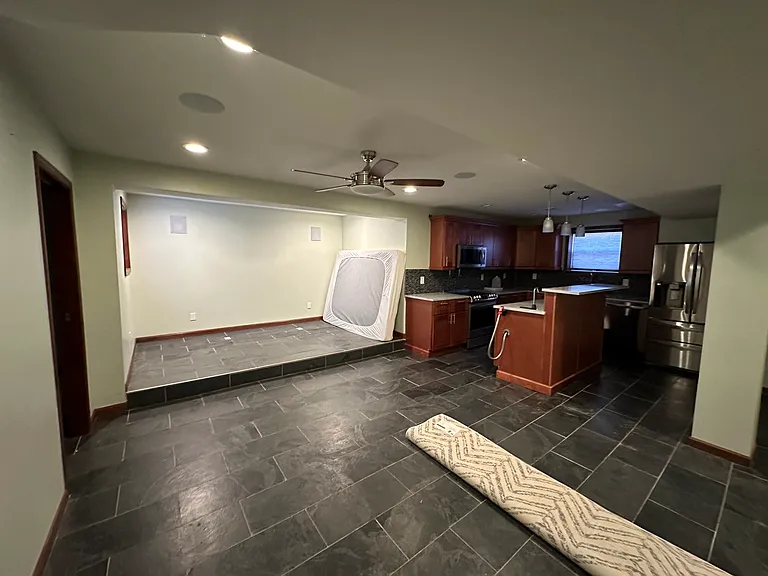 spacious finished basement, with large living space and home theater speaker setup, second kitchen with stainless steel appliances and quarts countertops