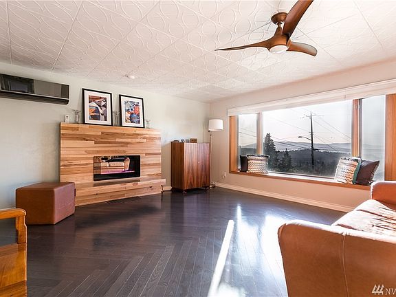 Living room with chevron wood floors and LG split for heat and air conditioning. High-end Minka ceiling fan.