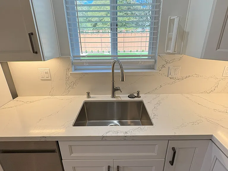 Kitchen sink, dishwasher and north-facing window that views the house's backyard.