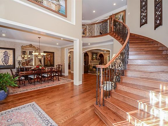 Entering into this beautiful property you will find a grand sweeping staircase with custom wrought iron detail. These solid wood floors are intricately laid and change design to designate from the entry way to the formal dining room.