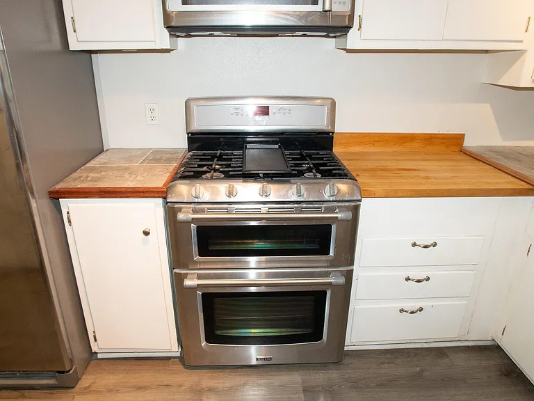 Full kitchen features plenty of cabinet space with a microwave, stove, oven, and two refrigerators.